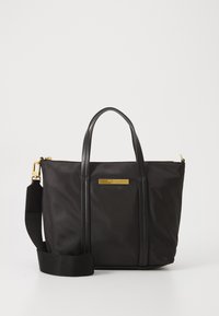 Musta nailoninen käsilaukku, jossa on nahkakahvat ja irrotettava olkahihna. Varustettu kultasävytetyillä yksityiskohdilla ja sileällä pinnalla, suorakulmaisen muotoilun ansiosta.