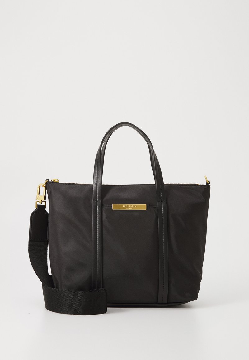 Bolsa de nylon preta com alças de couro e correia destacável. Apresenta acessórios em tom dourado e uma textura suave, com um formato retangular.