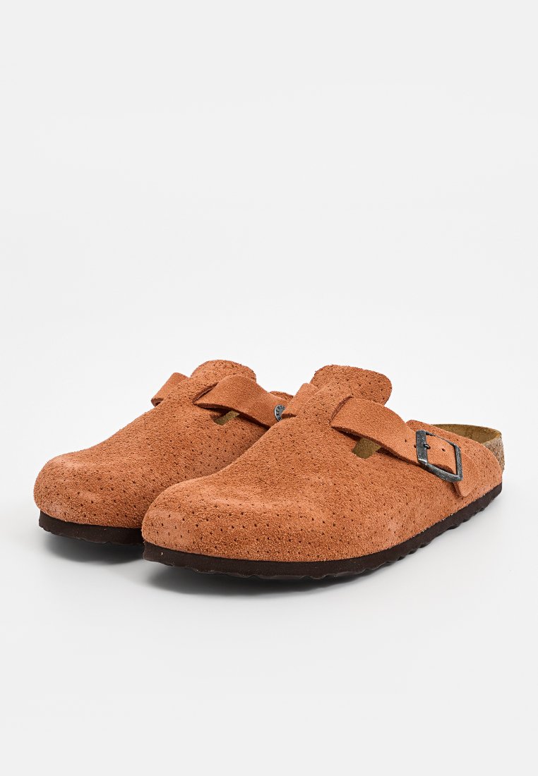 Rostfarbene Wildleder-Slipper mit perforierter Oberseite, verstellbarem Riemen und schwarzer strukturiertem Sohle.