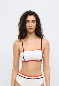 Μπικίνι τοπ σε εκρού χρώμα με κόκκινες και ναυτικά μπλε λεπτομέρειες, με λεπτές τιράντες και σχεδιασμό bandeau. Ψηλόμεσο κάτω μέρος που ταιριάζει με παρόμοιες χρωματικές λεπτομέρειες.