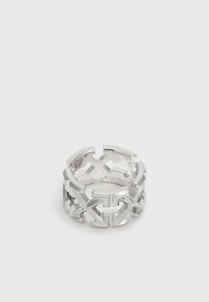 Ezüst nyitott gyűrű összekapcsolódó nyíl- és keresztalakzatokkal, amelyek geometriai mintát alkotnak.