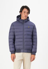 Puffer jacket in dark blue with a front zipper, padded design, ribbed cuffs, and a hood. Features a small embroidered logo on the chest.