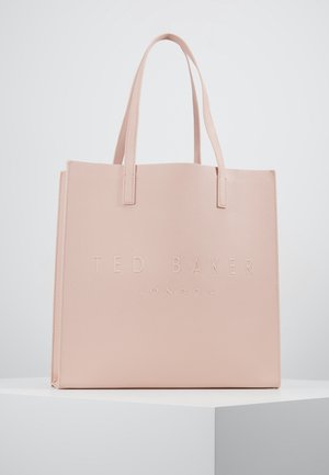 Bolsa tote rectangular de color rosa claro con dos asas, con el texto en relieve "TED BAKER LONDON" en el frontal, expuesta sobre un pedestal blanco.