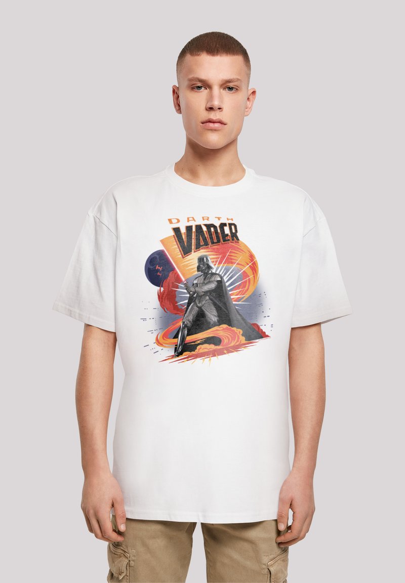 Hvid t-shirt med et grafisk design af Darth Vader, dekoreret med farverige svaj og eksplosioner. Løs pasform med korte ærmer og rund halsudskæring.