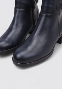 Botines de piel azul marino con puntera redonda, acabado liso, tacón bajo y cremallera lateral para un uso fácil.