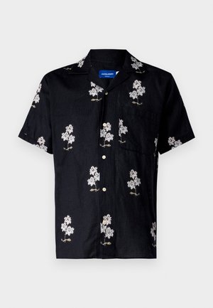 Chemise noire à manches courtes avec un motif floral brodé en blanc et or, fermeture à boutons et une poche poitrine. Tissu texturé.