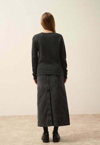 Tmavě šedý pletený svetr s texturovaným vzorem, doplněný dlouhou džínovou sukní. Černé platformové boty celkový outfit dokončují.