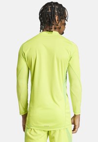 Langärmliges Sportshirt in leuchtendem Neon-Gelb, mit strukturiertem Mesh-Design und taillierter Silhouette. Branding-Detail am Saum.