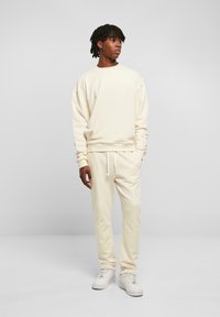 Cremefarbenes Sweatshirt und passende Jogginghose aus weichem Material, mit lockerer Passform, gerippten Bündchen und Kordelzugbund.