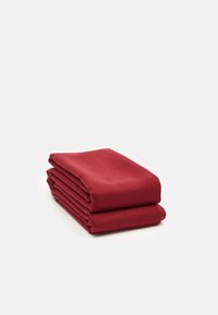 Couverture en polaire rouge foncé pliée avec une texture douce visible sur un fond blanc.