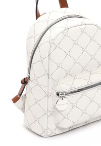 Sac à dos blanc à motifs avec poche avant zippée, tirettes de fermeture éclair argentées et sangles en cuir marron.