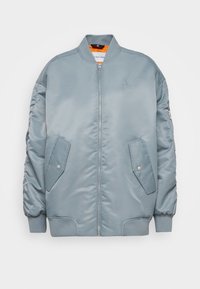 Giacca bomber azzurro chiaro realizzata in nylon liscio, con polsini e orlo a coste, due tasche laterali, chiusura frontale con zip e ricamo del logo.