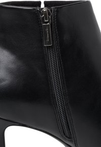 Stivale alla caviglia in pelle nera dal design elegante, con una zip laterale prominente e una finitura texturizzata. Il tacco alto esalta la forma.