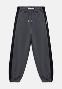 Szare dresy wykonane z miękkiego materiału, z czarnymi bocznymi paskami, elastycznym pasem z sznurkiem oraz ściągaczami na końcach nogawek.