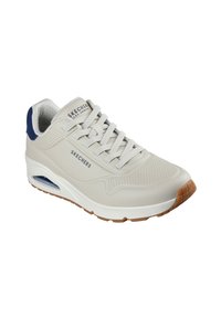 Skechers sneaker in light beige with a smooth leather upper, white midsole, navy accents on the heel, and textured rubber outsole.