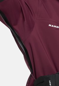 Bordeauxfarbene technische Stoffjacke mit einem Reißverschluss und strukturierten Akzenten. Logo in Weiß gedruckt. Für den Einsatz im Freien entworfen, mit funktionalen Elementen.