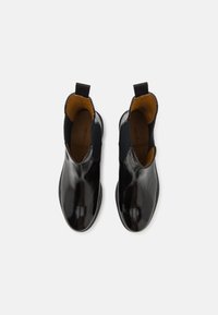 Sorte lær ankle boots med elastiske sidepaneler og trækloop. Glat, blank overflade med rund tå og kontrastfarvet brun inderside.