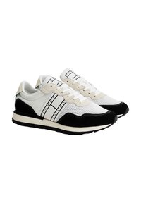 Zapatillas blancas y negras que combinan materiales de malla y ante, con un diseño elegante que presenta rayas y logotipos en los laterales, además de suelas texturizadas.
