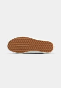 White sneaker with a textured, rubber gum sole featuring a diamond pattern. Clean lines and no visible logos or accents.
