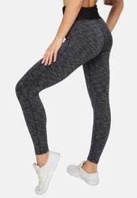 Schwarze, strukturierte Leggings mit einem hohen Taillenbund, die ein dezentes meliertes Muster aufweisen und eine schmale Passform haben, die sich an die Beine anpasst.