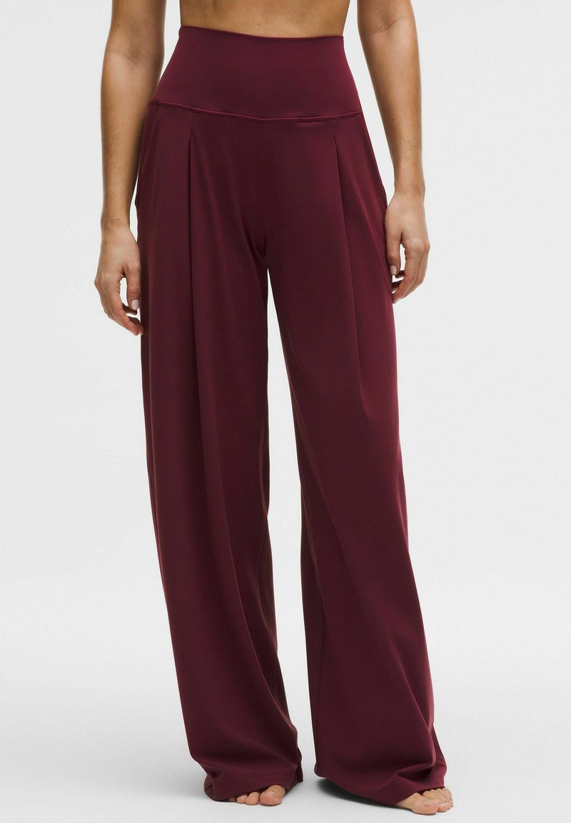 Pantalones de pierna ancha en tejido burdeos oscuro con cintura alta, con pliegues y una textura suave. Ideales para un ajuste relajado.