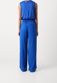 Blauw lichtgewicht jumpsuit met een mouwloos topje en wijde broekspijpen, voorzien van een geplooide tailleband en twee achterzakken. Gladde, effen textuur.