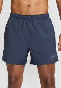 Tummansinisiä urheilushortseja, joissa on joustava vyötärö ja hillitty harmaa Nike-logo. Valmistettu kevyestä, sileästä kankaasta.