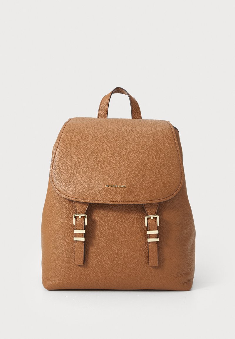 Sac à dos en cuir tan avec une surface texturée, un rabat avec deux accents de boucle en ton doré et une poignée supérieure pour le transport.