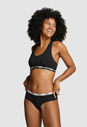 Schwarzer Sport-BH und passende Unterwäsche, mit einem elastischen Band in Weiß. Der Stoff ist glatt und enganliegend, mit einem Racerback-Design.