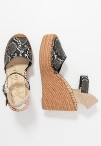 Černobílé sandály na klínu s hadím vzorem, přírodní podešví z tkaného lana, páskem kolem kotníku a béžovými texturovanými detaily.