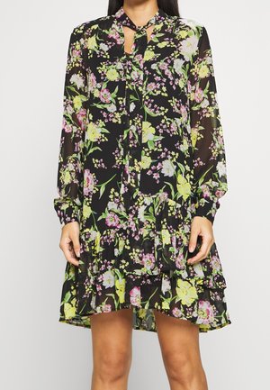 Schwarzes Blumenkleid mit langen Ärmeln, einem Schlüsselloch-Ausschnitt und gestuften Rüschen mit lebhaften grünen, pinken und gelben Blumenmustern.