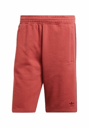 Red athletic shorts made of soft fabric, featuring an elastic waistband, side pockets, and a small brand logo near the hem.