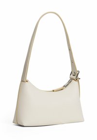 Kremowa skórzana torebka o zakrzywionym kształcie i pojedynczym regulowanym pasku. Posiada srebrny zamek błyskawiczny i kontrastujące jasnopomarańczowe wykończenie.