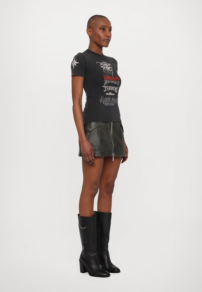 Black graphic t-shirt with short sleeves, featuring colorful text and designs. Paired with a black leather mini skirt and black knee-high boots.