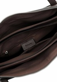 Intérieur d'un sac à main en cuir marron avec plusieurs compartiments, revêtu d'un tissu foncé et d'une étiquette de logo. Fermetures zippées pour plus de sécurité.