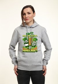 Felpa grigia con un graphic a tema Minecraft, che presenta alberi, blocchi e la scritta "MINA, DORMI, RIPETI" sul davanti. Materiale misto cotone.