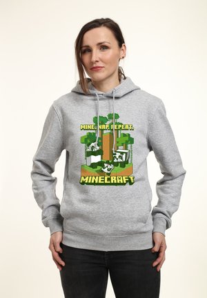 Felpa grigia con un graphic a tema Minecraft, che presenta alberi, blocchi e la scritta "MINA, DORMI, RIPETI" sul davanti. Materiale misto cotone.
