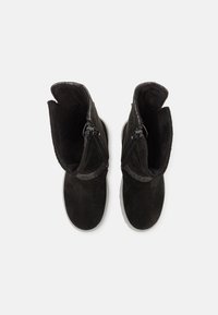 Botas de tobillo de ante negro con interior suave y dos cremalleras laterales. Acento decorativo gris cerca de la parte superior. Suela de goma plana.