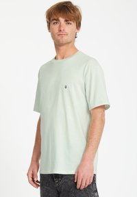 Lys grøn kortærmet T-shirt lavet af blødt bomuldsstof. Har en enkel rund hals og et lille broderet logo på brystet.