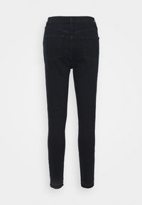Jean skinny noir en denim, avec une taille haute, des poches arrière et une coupe slim allant de la taille à la cheville. Détails de coutures visibles.
