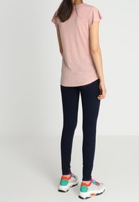 Light pink t-shirt with short sleeves, paired with dark blue skinny jeans and multicolored athletic sneakers. Simple, casual design.