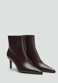Bottines en cuir bordeaux à bout pointu, texture brillante et fermeture éclair sur le côté. Dotées d'un talon fin et effilé pour une silhouette élégante.