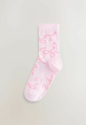 Lyserød bomuldsstrømpe med ribbet kant, prydet med et gentaget hvidt mønster af kursivskrivne bogstaver og et lille logo nær tåen.