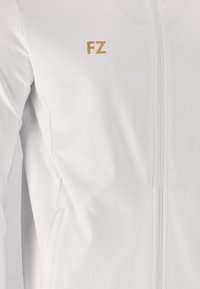 Hvid atletisk jakke med fuld frontlynlås, glat tekstur og et lille guld "FZ" logo øverst til venstre.