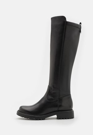 Bottes en cuir noir hautes avec une texture lisse, bout arrondi, semelle en caoutchouc robuste, et un détail de couture sur le côté. Accent de fermeture éclair en haut.