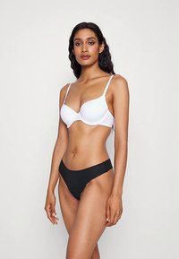 Biely podprsenka s kosticami a čierne tangá, hladká látka, nastaviteľné ramienka, bezšvový dizajn, minimalistické detaily, priliehavý strih.