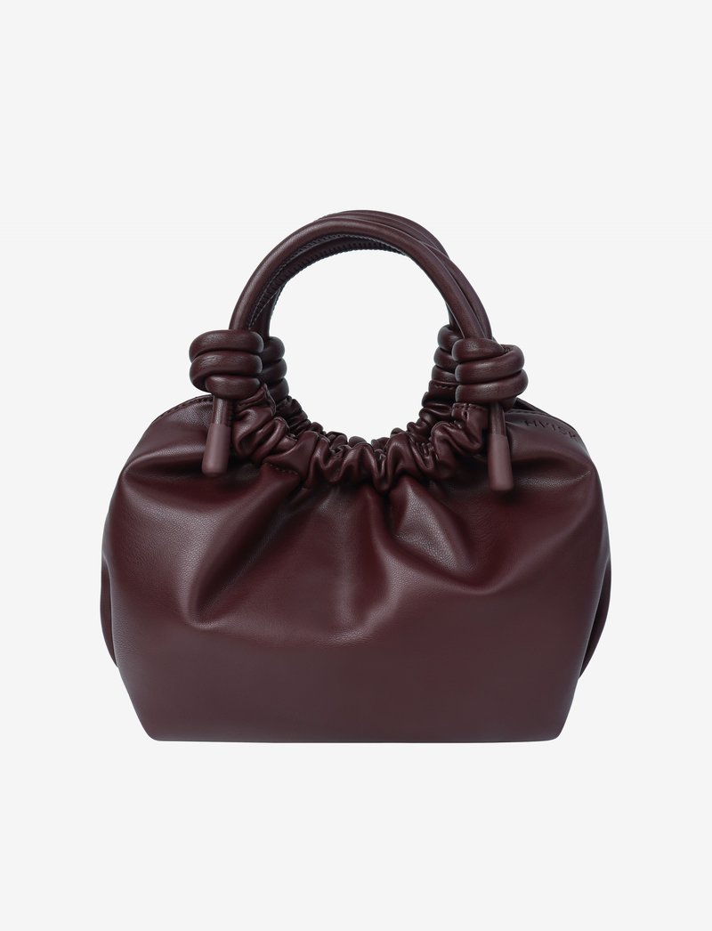 Burgundy leather handbag with a gathered top and knotted handles. Smooth texture with a rounded shape and minimalistic design.