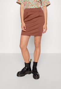 Brun mini kjol med två framfickor, tillverkad av ett mjukt material. Kombinerad med svarta lace-up kängor med tjock sula.