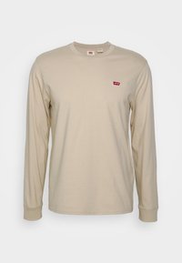 Beige langärmliges T-Shirt aus weicher Baumwolle, mit einem runden Halsausschnitt und einem kleinen roten Levi's-Logo auf der linken Brust. Glatte Textur.