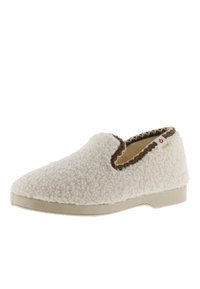 Pantofole slip-on color crema con tessuto in pile testurizzato e bordi marroni intorno all'apertura, dotate di suola in gomma.